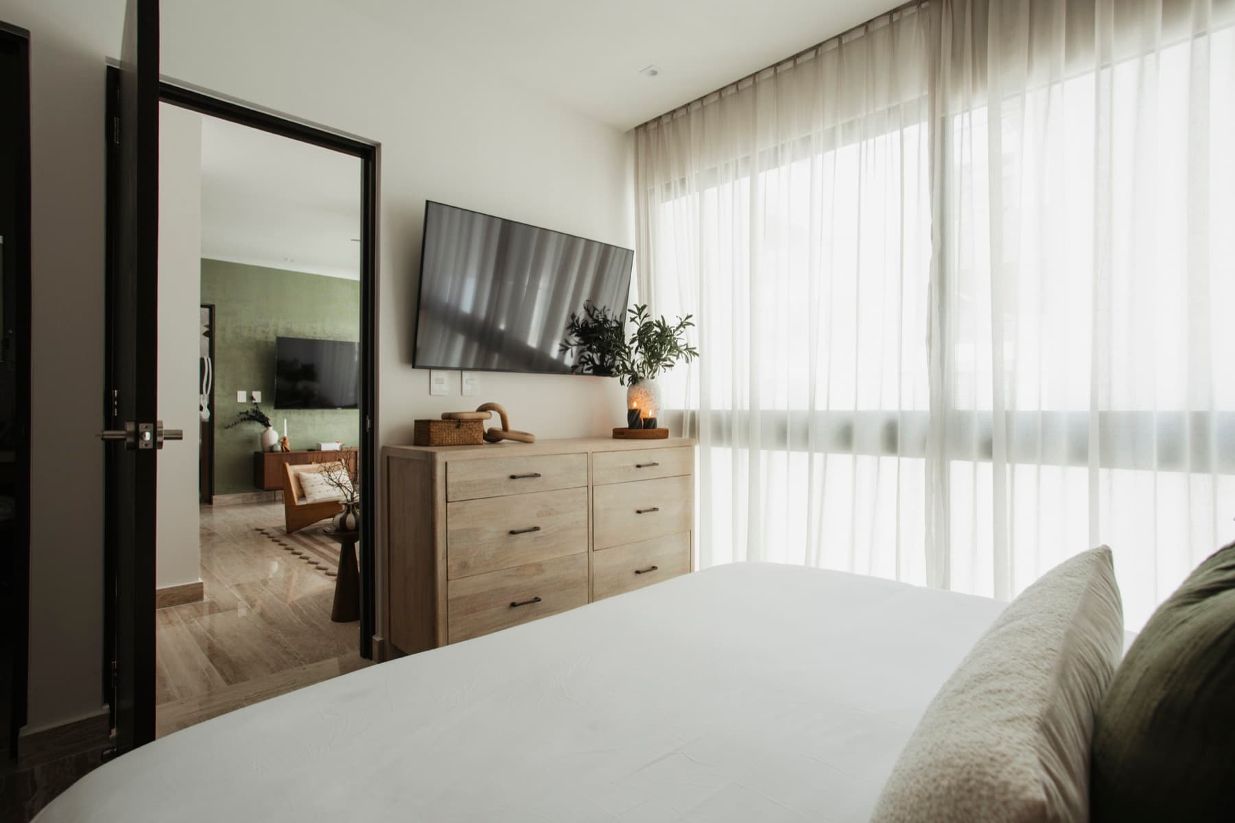 Ceiba at 25 bedroom with dresser and wall-mounted TV